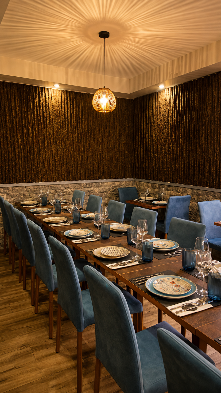 Sala de jantar intimista com cadeiras azuis, mesas de madeira e iluminação quente